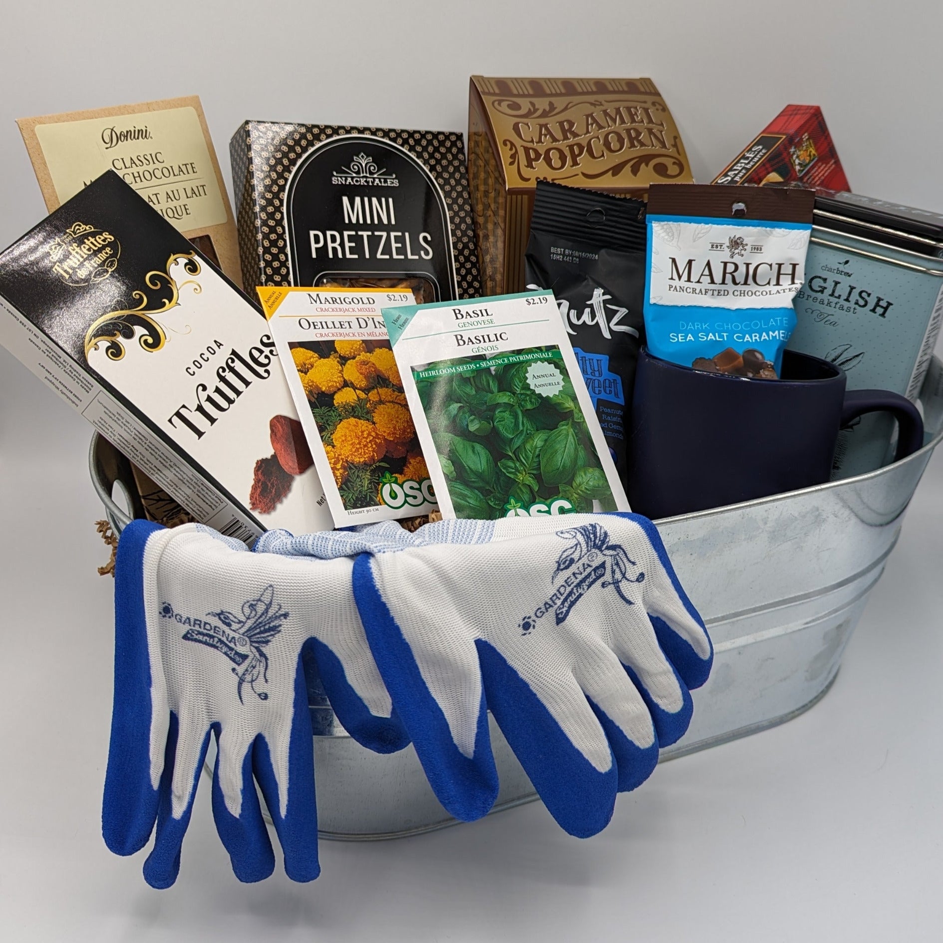 Garden Lover's Basket filled with garden gloves, seeds, ceramic mug, tea, and a variety of snacks.