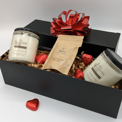 Candle Gift Box featuring two F & L candles, Thrive bath salts, and assorted chocolates.
